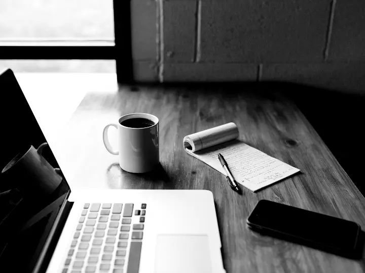Notebook sobre mesa de trabalho, em preto e branco